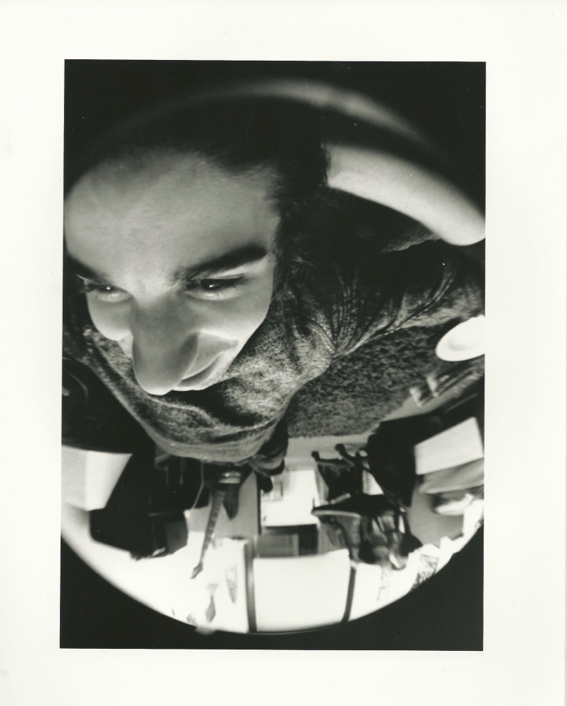 Black-and-white fisheye portrait of Alex Kalil looking down into the lens in a studio at RISD.